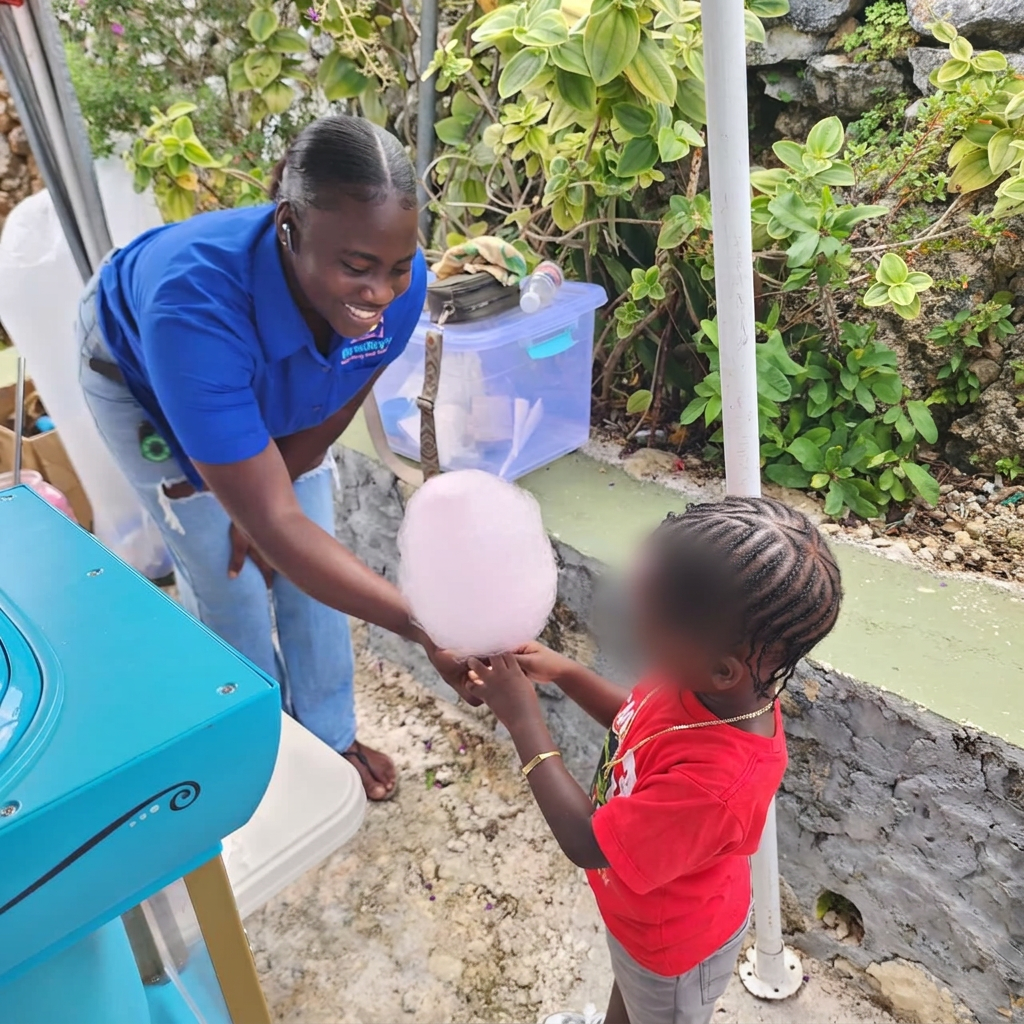 Team member handing cotton candy to a young guest